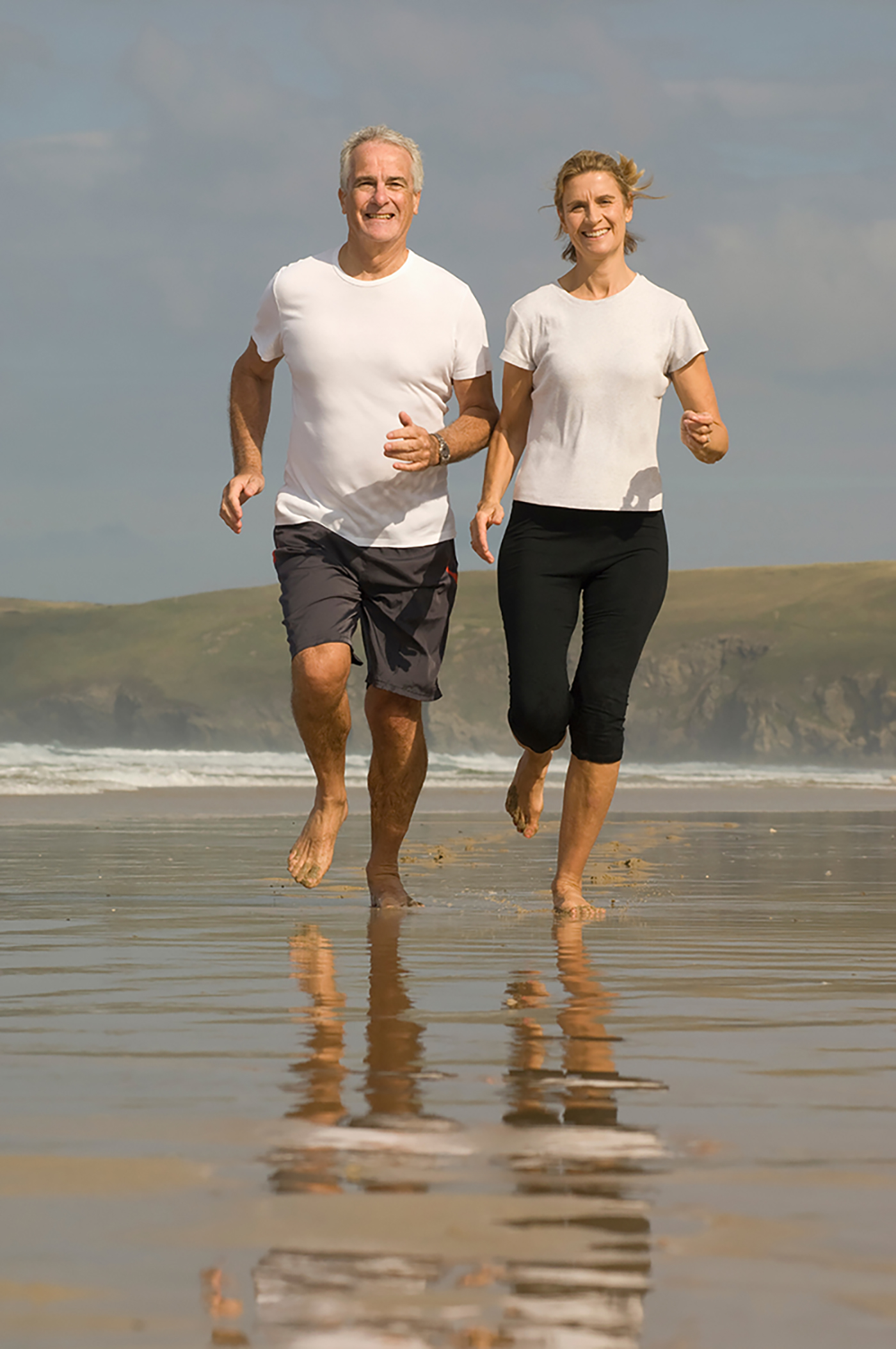 image of a mature couple running on the beach